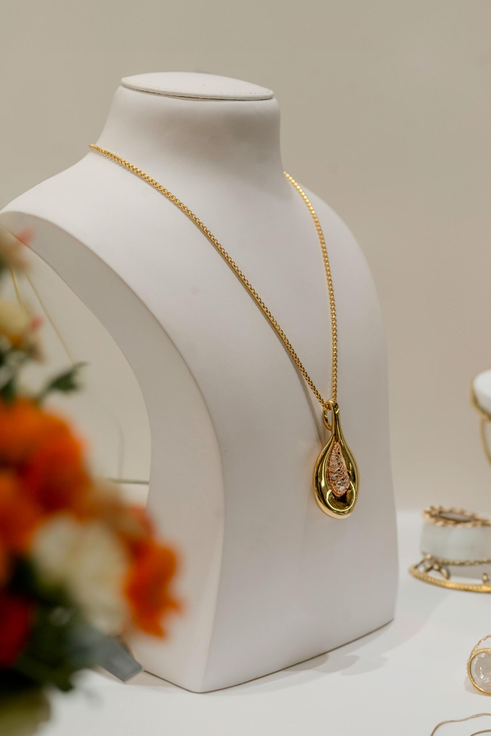Elegant gold necklace showcased on a bust in a luxury setting with soft lighting.